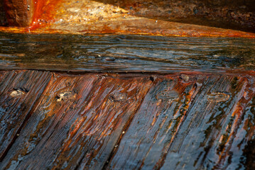 Wet, shiny, worn floor boards of an old, wooden ship wreck on the Mediterranean coast in Israel.