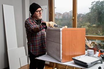 Mature man painting furniture