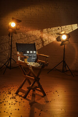 Close up shot of cinema clapperboard standing on director's chair popcorn scattered around, rays of...