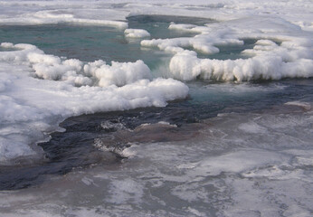 unusual and delicate ice with thawed areas and cascades on the winter river