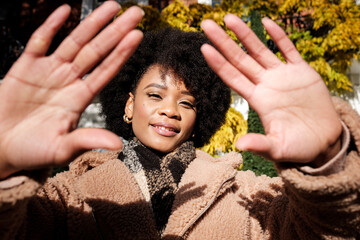 Smiling young black woman showing palm of hands outside.
