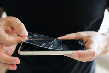 Process unrecognisable repairman is removing broken and old tempered glass screen protector from...