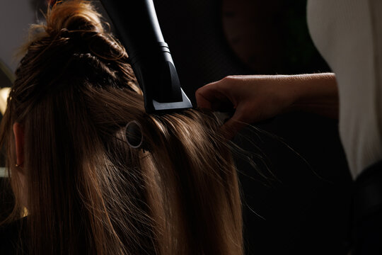 hairdresser blow-drying hair with a comb in a beauty salon, blow-drying hair close-up