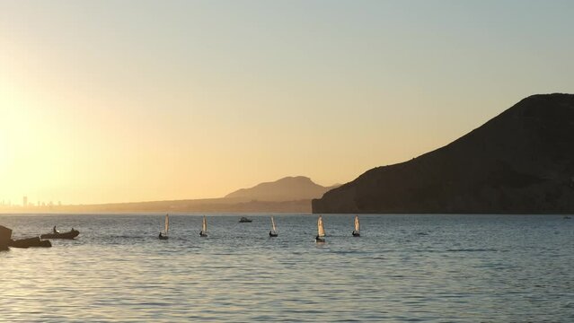 Sailors sport competition. Yacht club regatta in the open sea. Small yachts for training at sea. Yachting and sailing training. Summer sport. Athletes in the regatta. Calpe city, Spain.