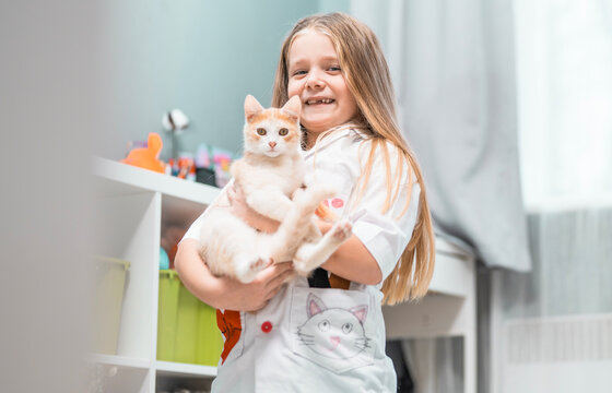 Cute little girl plays veterinarian. Role play ideas for kids. Child with kitten at home. School girl in a vet cotume with a cat. Daycare games.