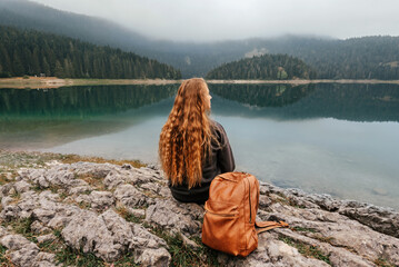Woman Sitting Alone on Rock by Mountain Lake