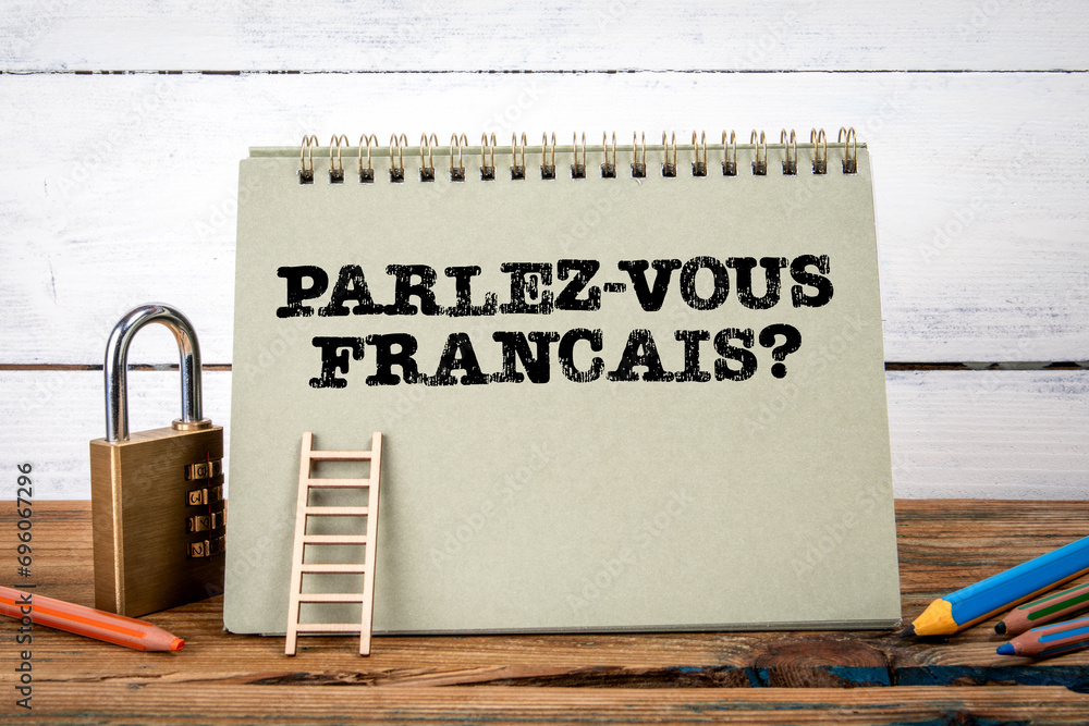 Wall mural Do you speak french? Written in French. Green notepad on wooden texture table and white background