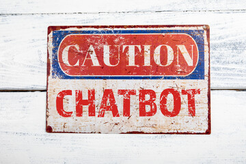 Chatbot Concept. Metal CAOTION plate with text on a white wooden background