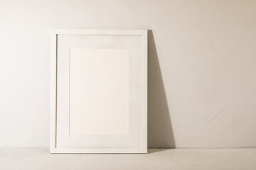 White frame leaning on white plaster wall
