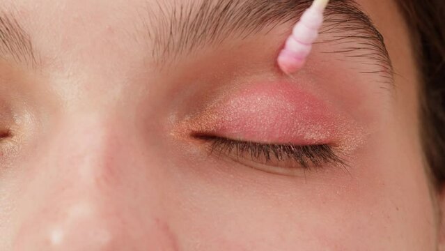 Eye shadow makeup to the upper eyelid, close-up. Makeup artist applies a bright eye shadow with a makeup brush.Tutorial master class of professional makeup. 