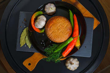 Circassian Adyghe round smoked cheese on a black background