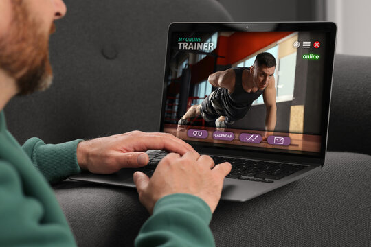 Personal trainer online. Man viewing website via laptop at home, closeup