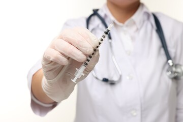 Doctor holding medical syringe on white background, closeup