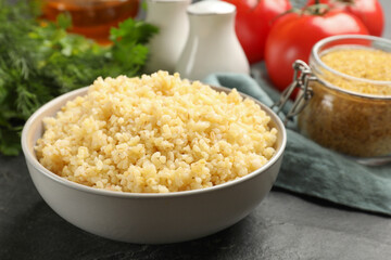 Delicious bulgur in bowl on black table, closeup