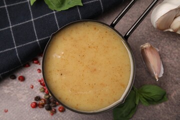 Delicious turkey gravy, basil, peppercorns and garlic on brown textured table, flat lay