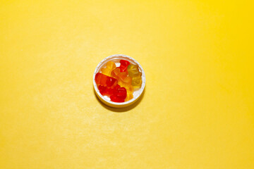 children's vitamins jelly bags in lids from jars on a yellow background