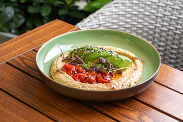 Hummus with caramelized tomatoes and avocado. Healthy vegan food, Israeli cuisine