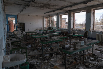 Fototapeta na wymiar Broken windows, broken tables and tools. There is a lot of debris around. This is the classroom of a destroyed school in the Donetsk region