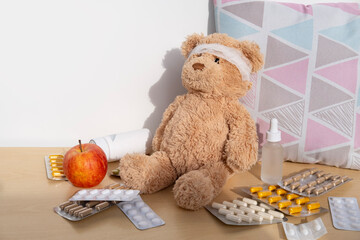 teddy bear with bandaged head, surrounded by scattered medicines and pills, health, care and...
