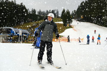 one mature man in winter sportswear, downhill skier on snowy mountain with ski poles, Skiing on...