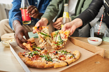 Close up shot of diverse friends hands picking up slices of appetizing pizza with sauce and...
