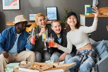 Medium long shot of happy diverse young friends at home taking selfie holding fizzy drinks after...