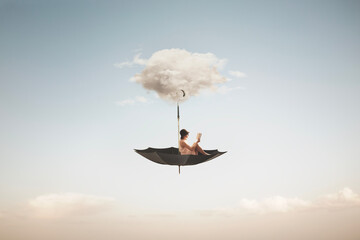 surreal woman reading a book flies on an overturned umbrella - 696090205