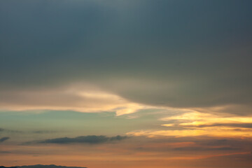 Warm foggy sunset sky with pastel romantic clouds, last rays of sun on the horizon before sunset