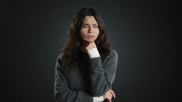 The girl is thinking. She places one hand under her chin and immerses herself in her thoughts. High quality 4k footage