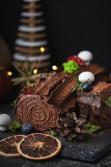 Traditional  French Christmas chocolate dessert  BûchedeNoël (Yule log). Christmas festive pastry in the shape of a log on the dark concrete background