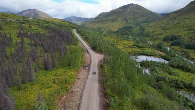 ALASKA - 2023 - Excellent aerial footage of a car driving up Alaska's Hatcher Pass into the green mountains.