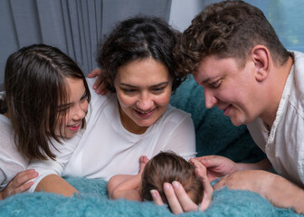 appy family with a newborn baby. Mom and dad looking tenderly at the baby.