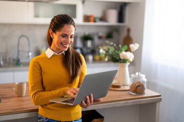 Confident businesswoman doing research over wireless computer while standing in home office.