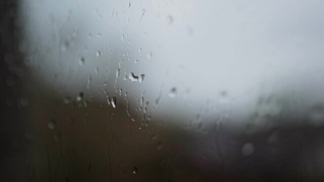 Mesmerizing raindrops gracefully cascading down the window on a rainy day, capturing the beauty of a tranquil and soothing atmosphere.