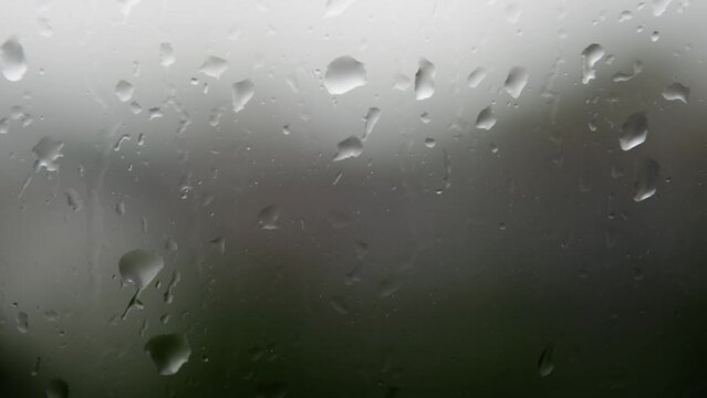Mesmerizing raindrops gracefully cascading down the window on a rainy day, capturing the beauty of a tranquil and soothing atmosphere.