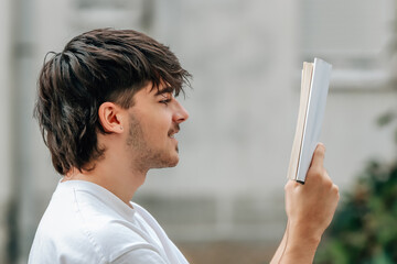 young man with book reading outdoors