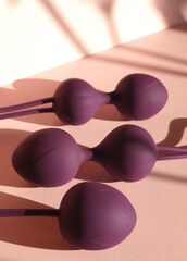 Purple kegel balls in a soft pink background / Vaginal balls sex toy concept. Geisha balls pelvic floor healthcare / Ben wa balls feminine concept. 