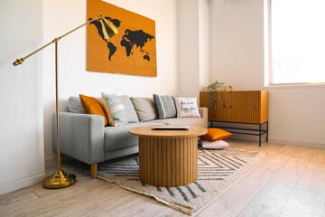 Interior of stylish living room with cozy sofa and modern laptop on coffee table