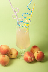 peach juice on green background with colorful and fun straws