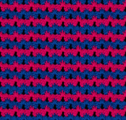 Seamless knitted texture in floral style. The pattern is crocheted from multicolored cotton yarn. Blue-pink color combination.