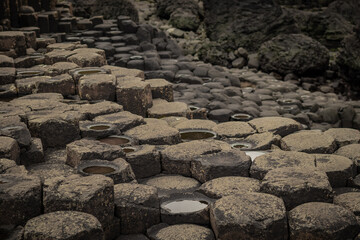 Detail of hexagonal stones or pillars at Giants causeway in northern ireland, majestic basalt pillars at the beach on a cloudy day.