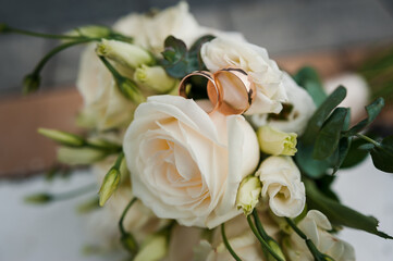 Gold wedding rings on a wedding bouquet with white flowers