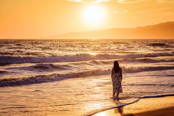 Young lady walking in the sunset on Santa Monica beach