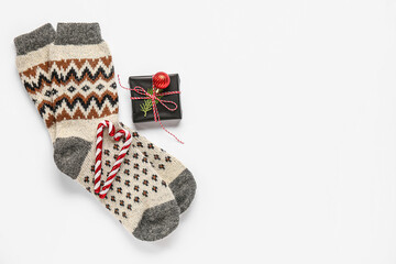 Warm socks with gift box and candy canes on white background