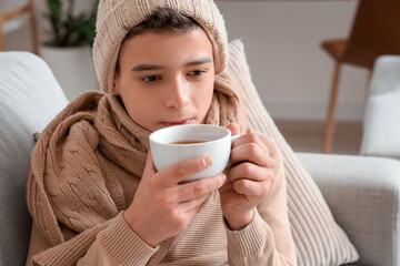 Sick little boy drinking tea at home, closeup