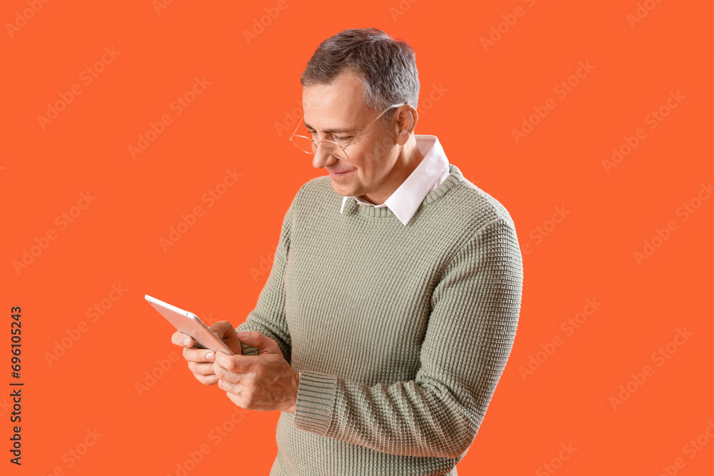 Sticker mature man in eyeglasses using tablet computer on orange background