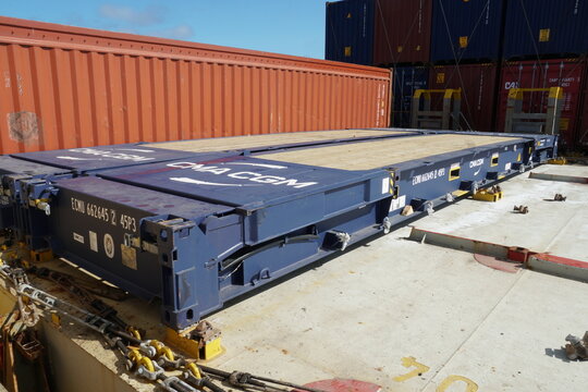 Savannah, USA 12 02 2023: Blue empty flat rack container secured on deck of container vessel. Next is loaded fully closed red 40 feet unit lashed to the hatch cover.