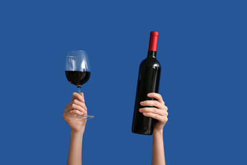 Female hands with bottle of wine and glass on color background