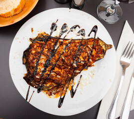 In center of frame is plate with hearty snack. Eggplant stuffed with young cheese baked under egg...