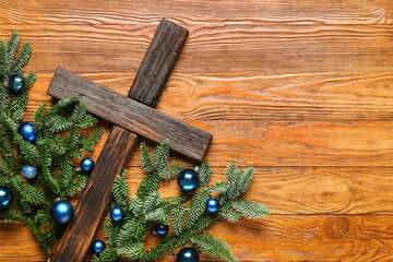 Cross with fir branches and balls on wooden background. Christmas story concept